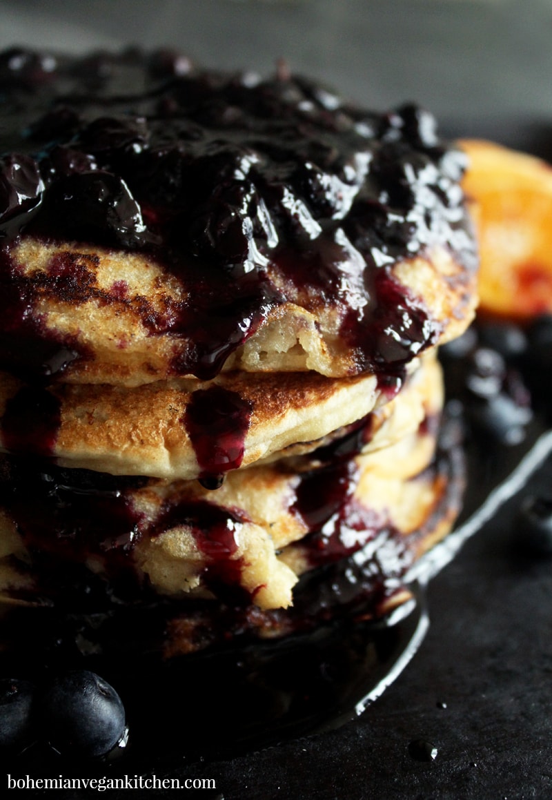 Learn the secret to making moan-worthy vegan pancakes + enjoy this simple recipe with homemade blueberry syrup! Easy to pull together, and includes instructions for gluten-free pancakes. #veganpancakes #veganpancakesglutenfree #veganpancakesrecipe #veganpancakesblueberry #veganpancakesblueberrysauce #bohemianvegankitchen