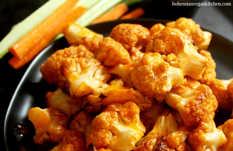 Spice up your party with these KILLER vegan buffalo cauliflower wings! Easy to pull together, you only need 10 minutes to assemble- let the oven do the rest! Serve with carrot and celery sticks, plus vegan ranch dressing to cool your taste buds. #veganbuffalocauliflower #veganbuffalocauliflowerwings #veganbuffalocauliflowerrecipes #veganbuffalocauliflowerglutenfree #bohemianvegankitchen