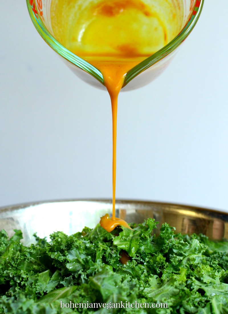 drizzle shot of dressing being poured on kale salad