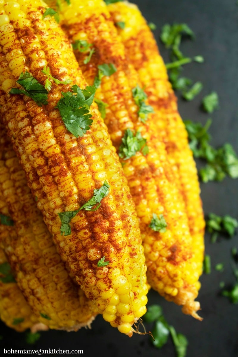 Need a summertime side dish that's vegan, allergy-friendly, and doesn't use imitation animal products? Try this healthy version of street corn, which takes only 5 minutes prep time and can be ready to eat in 30 minutes! #veganstreetcorn #dairyfreestreetcorn #bakedcornonthecoboven #bakedcornonthecob #vegansidedisheasy #bohemianvegankitchen