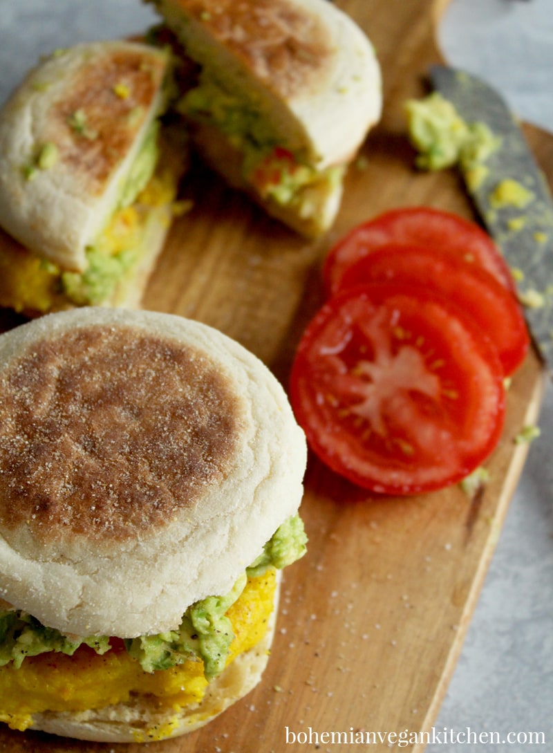 For a delicious (yet simple) breakfast, enjoy these vegan egg sandwiches, which are topped with juicy tomato sliced and smashed avocado! Completely vegan and soy-free, these breakfast sandwiches can be made gluten-free by using GF english muffins. #veganeggsandwich #veganeggsandwichbreakfast #veganeggrecipes #veganeggbreakfastsandwich #veganegg #bohemianvegankitchen