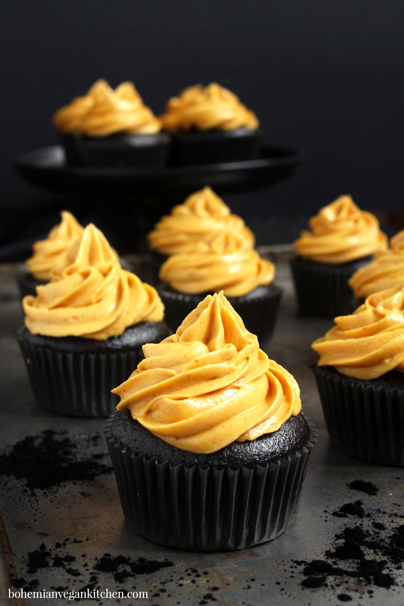 Make Halloween wicked delicious with these black chocolate coffee flavored cupcakes, topped with vibrant pumpkin pie frosting. These vegan Halloween cupcakes are easy to make, but result in a stunning finish that will put a spell on anyone who tastes them! #veganhalloweencupcakes #veganhalloweenrecipes #veganhalloweentreats #blackdesserts #veganhalloweendesserts #veganhalloweenfood #bohemianvegankitchen