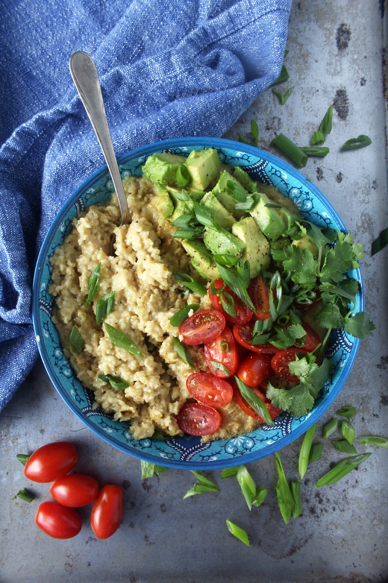 Who says oatmeal has to be sweet? I LOVE making this cheesy + savory vegan oatmeal, which takes less than 10 minutes to make! Topped with fresh tomatoes, diced avocado, cilantro, and green onions, this easy breakfast is the perfect way for your family to start the day. #veganbreakfastrecipes #veganbreakfasthealthy #veganbreakfastideas #quickveganbreakfast #veganoatmealrecipes #veganoatmealsavory #bohemianvegankitchen 