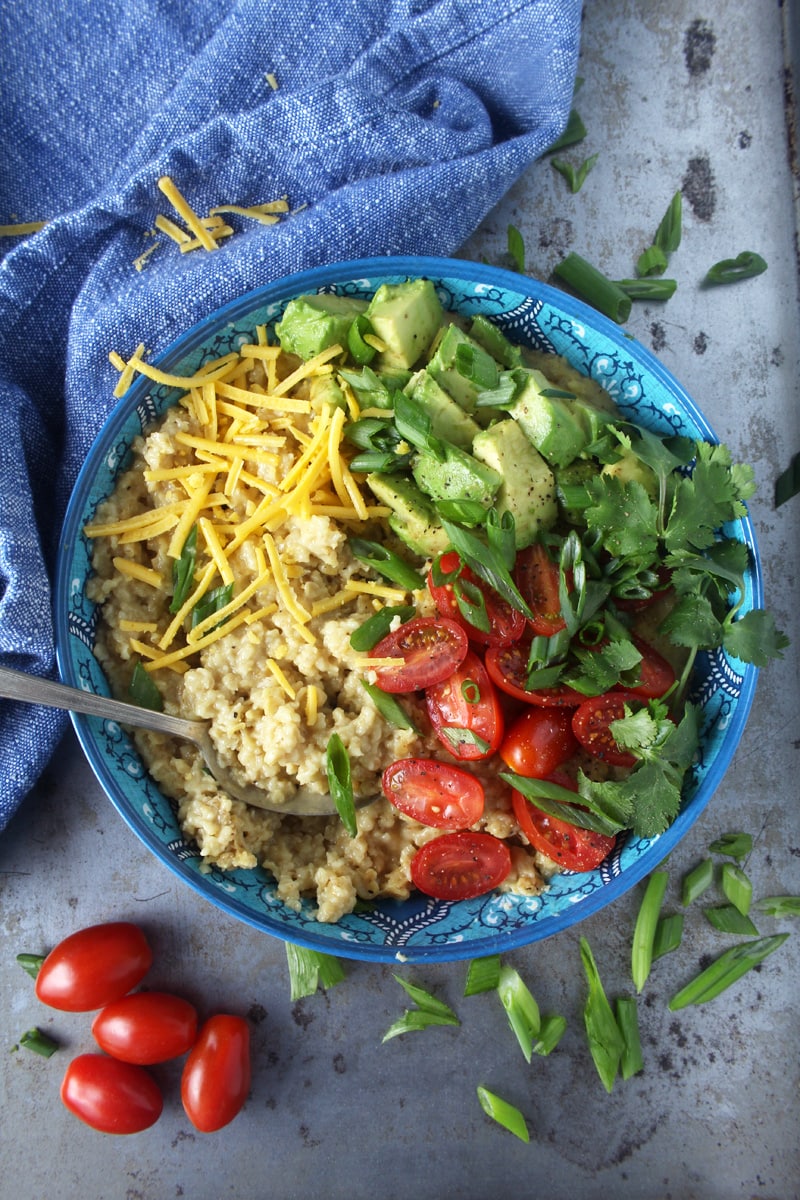 Who says oatmeal has to be sweet? I LOVE making this cheesy + savory vegan oatmeal, which takes less than 10 minutes to make! Topped with fresh tomatoes, diced avocado, cilantro, and green onions, this easy breakfast is the perfect way for your family to start the day. #veganbreakfastrecipes #veganbreakfasthealthy #veganbreakfastideas #quickveganbreakfast #veganoatmealrecipes #veganoatmealsavory #bohemianvegankitchen 