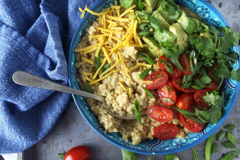 Who says oatmeal has to be sweet? I LOVE making this cheesy + savory vegan oatmeal, which takes less than 10 minutes to make! Topped with fresh tomatoes, diced avocado, cilantro, and green onions, this easy breakfast is the perfect way for your family to start the day. #veganbreakfastrecipes #veganbreakfasthealthy #veganbreakfastideas #quickveganbreakfast #veganoatmealrecipes #veganoatmealsavory #bohemianvegankitchen 
