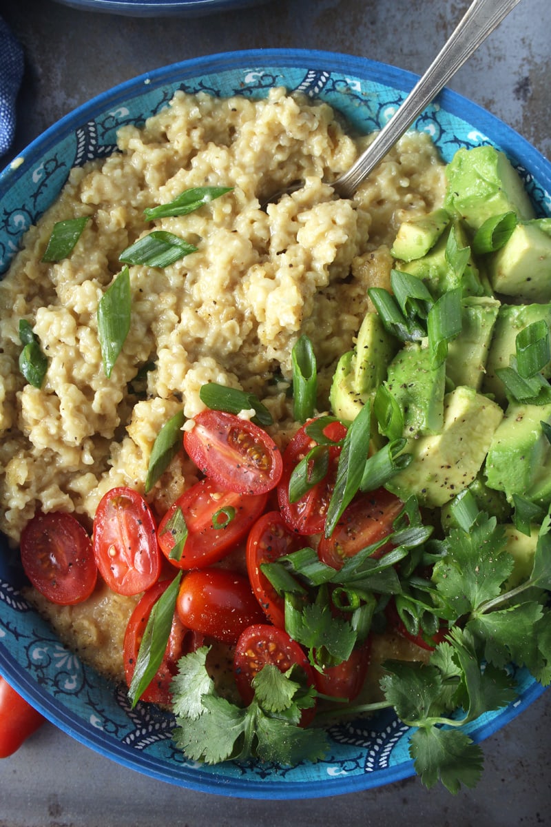 Who says oatmeal has to be sweet? I LOVE making this cheesy + savory vegan oatmeal, which takes less than 10 minutes to make! Topped with fresh tomatoes, diced avocado, cilantro, and green onions, this easy breakfast is the perfect way for your family to start the day. #veganbreakfastrecipes #veganbreakfasthealthy #veganbreakfastideas #quickveganbreakfast #veganoatmealrecipes #veganoatmealsavory #bohemianvegankitchen 