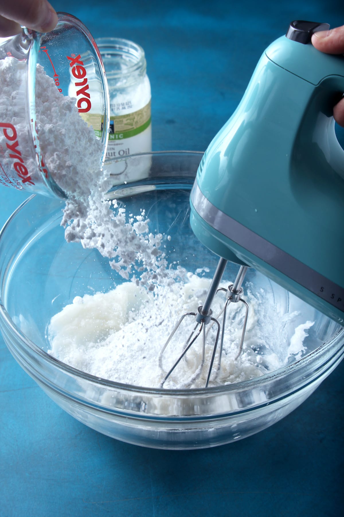 picture of powdered sugar being poured into coconut frosting.