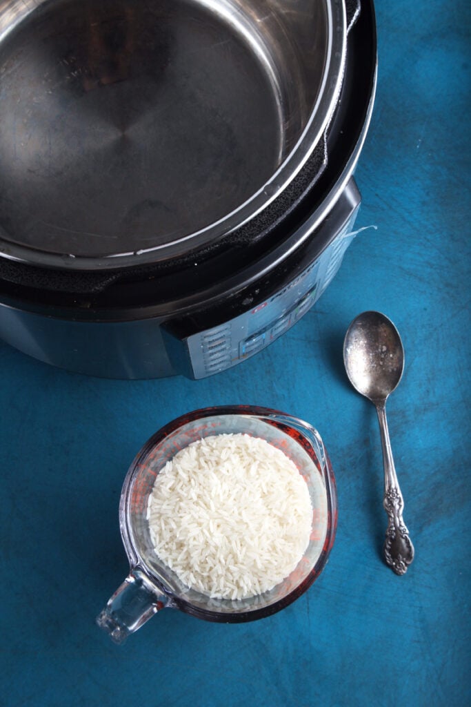 Picture of pressure cooker and white rice in cup.