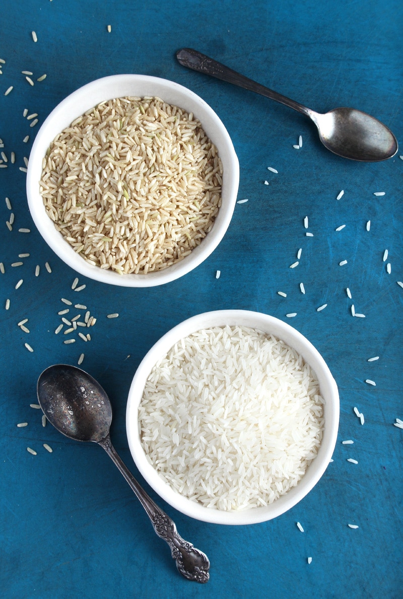 Picture from above: brown rice and white rice in bowls with spoons.