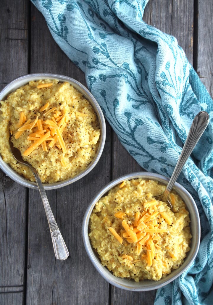 two bowls full of cheesy cauliflower grits with spoons