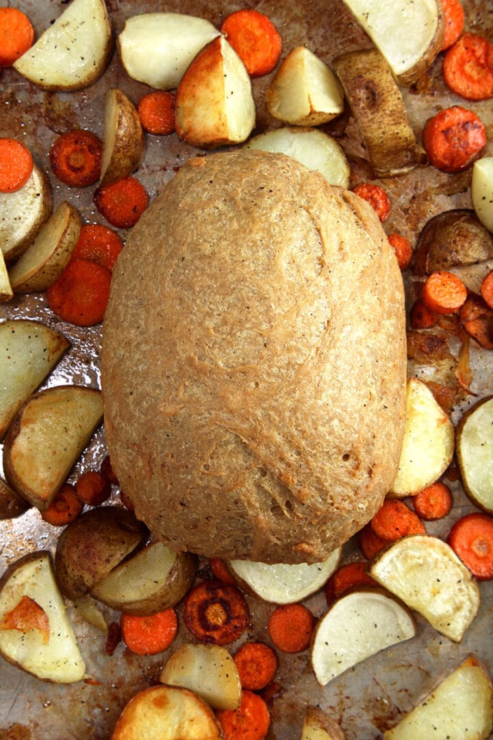 picture of vegan turkey on tray, unsliced with carrots and potatoes