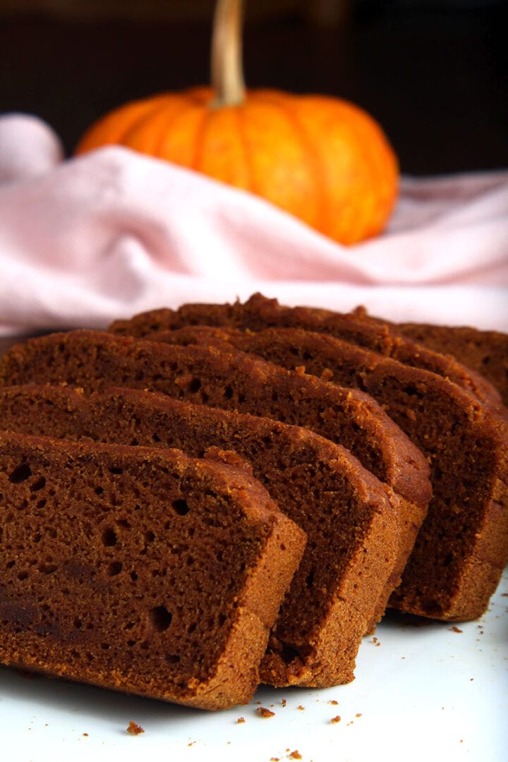 side picture of sliced gluten free vegan pumpkin bread with a pumpkin and napkin 